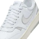 Championes Nike Gamma Force de diseño urbano, con base blanca y detalles en plateado metalizado en el logo lateral y el talón. Presenta una suela de plataforma en tono crema con acabado gris en la parte inferior.
