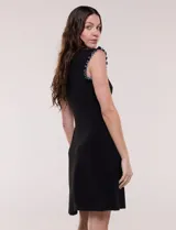 Vestido corto azul marino de seda fría elastizada, con escote redondo y sisas decorados con volados fruncidos en contraste de color blanco. Presenta corte entallado en la parte superior y falda acampanada.