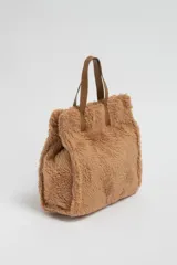 Bolso tipo tote de tela sherpa color tostado, con doble asa corta de cuero sintético marrón.