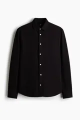 Camisa negra de punto elástico con cuello italiano, cierre frontal de botones y mangas largas.