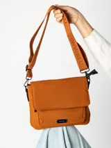Bandolera terrano de color marrón con solapa frontal y cierre magnético, bolsillo frontal exterior con placa metálica de la marca, y correa ajustable de cincha con inscripciones.