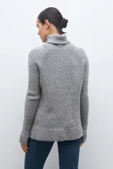 Sweater gris melange de tejido buclé con cuello alto y mangas largas.