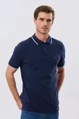 Remera polo de piqué azul marino, con cuello y puños de mangas cortas con ribete blanco en contraste, cierre frontal de dos botones y pequeño logo bordado en el pecho.