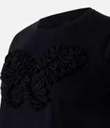 Remera negra de algodón con cuello redondo, manga corta y bordado frontal en relieve con forma de mariposa.