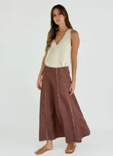 Pollera larga de lino color blanco, con corte acampanado y paneles verticales con costuras a la vista.