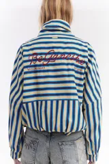 Chaqueta bomber de algodón con estampado a cuadros en tonos azules, amarillos y marrones, cuello alto y cierre frontal descentrado con botones. Cuenta con mangas abullonadas y puños elásticos.