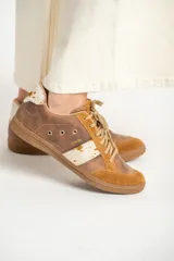 Zapatillas bajas color marrón con detalles en cuero con estampado de vaca en los laterales y talón.