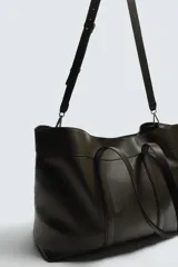 Bolso tipo shopper de piel en color negro, con diseño minimalista, doble asa de mano y compartimento principal con cierre magnético.