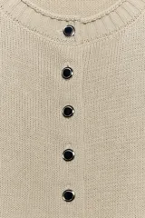 Chaqueta de punto de cuello redondo y manga larga, con cierre frontal de botones metálicos y acabados en rib.