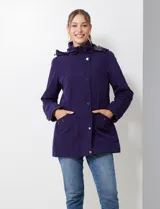 Gabardina impermeable de mujer, color morado oscuro, con capucha desmontable y cierre frontal oculto con botones a presión. Presenta bolsillos delanteros y ajuste interno en la cintura.