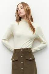 Polera de cuello alto y manga larga, confeccionada en tejido suave y elástico, con un ajuste al cuerpo.
