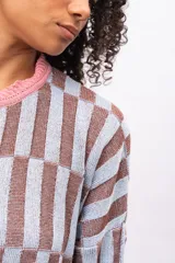 Saco de punto con diseño de bloques geométricos en tonos celeste y marrón, con cuello redondo, cierre frontal de botones y terminaciones en color rosado.