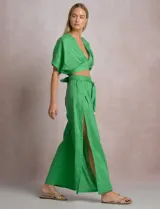 Pantalón palazzo de lino color verde, modelo de tiro alto con cintura elastizada y cinto lazo incorporado. Cuenta con aberturas laterales pronunciadas en las piernas y corte amplio.