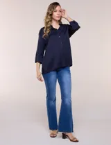 Camisa de satén azul marino con cuello mao, escote en V y mangas tres cuartos con hombro caído. Presenta silueta holgada, cierre frontal con botones y ruedo asimétrico.