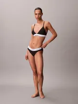 Bralette Calvin Klein de corte triangular, color negro con estampado geométrico de monogramas y banda elástica inferior blanca con el logotipo de la marca. Cuenta con tirantes finos ajustables.