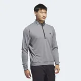 Buzo gris de golf Adidas con medio cierre frontal y logo de la marca en el pecho. Confeccionado en tejido de punto doble ligero y suave.