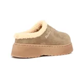 Pantuflas tipo sueco de gamuza color taupe, con interior forrado en corderito sintético color crema y plataforma de goma al tono. Presenta el logo de la marca bordado en el lateral.