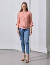 Blusa blanca de gasa marca Zac & Rachel, con cuello a la base, escote en V, abertura central con botones, bolsillo aplicado en el pecho y mangas largas regulables con presilla y botón. Tiene terminación opcional de nudo en el ruedo.