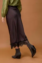 Falda midi de seda con estampado de lunares rojos sobre fondo oscuro, con detalle de encaje negro en el ruedo.