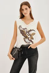 Musculosa de viscosa color blanco con escote en V y detalle de tachas en el borde del cuello. Presenta un estampado frontal de un águila en tonos tierra.