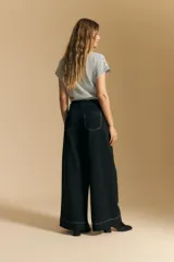 Pantalón largo color crema, tiro alto, de corte recto y ancho. Presenta costuras visibles en contraste y bolsillos delanteros.