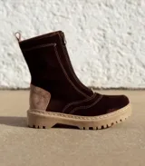 Bota tipo borcego de cuero color marrón oscuro con detalles en gamuza beige en el talón. Presenta cierre frontal, suela track de goma color beige con costuras visibles y forro interior de felpa.