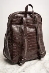 Mochila marrón con estampado de piel de cocodrilo, con cierre superior y bolsillo frontal con cierre.