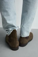 Bota estilo Chelsea de piel con acabado serraje color beige, con elásticos laterales para facilitar el calce, horma redonda y suela a tono con ligero tacón.