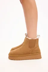 Bota tipo chelsea de gamuza color camel, con interior forrado en piel sintética, elásticos laterales y plataforma alta con suela dentada.
