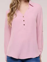 Blusa verde de calce holgado y caída fluida, confeccionada en tejido tipo crepé. Cuenta con cuello camisero con solapa, escote en V y cierre parcial al frente con tres botones metálicos. Las mangas son largas con puños abotonados.