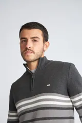 Sweater de punto para hombre con diseño de rayas horizontales en tonos azul marino, azul y mostaza. Presenta cuello alto con medio cierre frontal, mangas largas con puños acanalados y logo bordado en el pecho.