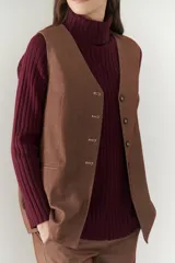 Chaleco azul con cuello en V y cierre frontal con botones marrones.