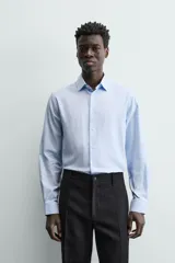 Camisa de hombre color beige claro, de corte slim fit, con cuello italiano, manga larga y cierre frontal de botonadura.