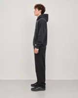 Canguro con capucha y cordones ajustables, color negro con efecto lavado. Presenta un bolsillo frontal tipo canguro y estampado gráfico pequeño en el pecho con el logo de la marca.