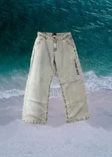 Pantalón de jean celeste con corte amplio, bolsillos delanteros y traseros, y estampado con el texto "Glassy Waves" en la pierna derecha.