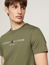 Remera de manga corta Tommy Hilfiger de color verde militar, con cuello redondo y el logo de la marca bordado en el pecho junto con el texto 'EST. 1985'.