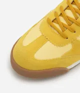 Championes amarillos con detalles en lila, de estilo vintage con punta redonda, cordones y recortes contrastantes. Suela marrón con base blanca.