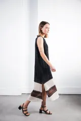 Vestido midi tejido en punto canalé negro con detalles en lurex plateado. Presenta calado artesanal en el ruedo, abertura lateral y etiqueta de cuero en la parte trasera del cuello.