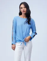 Blusa tejida color celeste con lurex, de manga larga con aberturas y apliques de brillo. Ruedo anudado.
