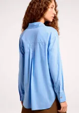 Camisa de algodón de manga larga con diseño de rayas verticales en tonos celeste y blanco, corte recto y cuello clásico.