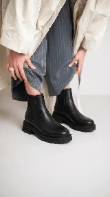 Bota tipo chelsea de cuero con acabado desgastado, paneles laterales elásticos y suela track robusta.