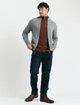 Cardigan de punto gris con cuello alto, cierre frontal de metal con doble cursor y bolsillos laterales. Presenta puños y cuello en tejido canalé.