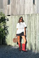 Botas de caña alta estilo cowboy, color rojo brillante, con bordados decorativos en hilo blanco contrastante. Presentan punta afilada y tacón bajo y angular.