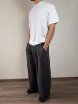 Pantalón de vestir de corte baggy, color gris oscuro, con pinzas frontales y bolsillos laterales.