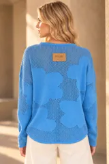 Buzo de tejido de punto calado color celeste, con diseño de flores, escote redondo y mangas largas.