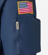 Campera rompevientos azul marino con capucha, cierre frontal y bolsillos laterales. Presenta estampado de NASA en el pecho, parche de bandera estadounidense en la manga y bolsillo utilitario en el brazo.
