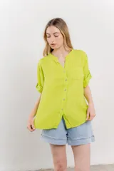 Camisa de lino color verde lima, de calce relajado, con cuello mao, botones al frente y bolsillo en el pecho. Las mangas son cortas y pueden usarse arremangadas.