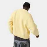 Suéter de punto grueso color amarillo, con corte cuadrado y ligeramente corto. Presenta cuello redondo, mangas largas con puños ajustados y el logo de la marca Eme Studios junto a la frase 'curated by ben ice' en jacquard oscuro en el centro del pecho.