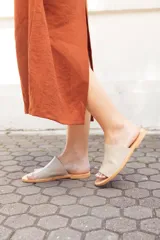 Sandalias bajas color beige con base marrón, de cuero y hechas a mano en Uruguay.