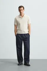 Polo de manga corta color verde oliva, con cuello solapa y abertura frontal tipo polo. Presenta una textura acanalada vertical y un calce regular.